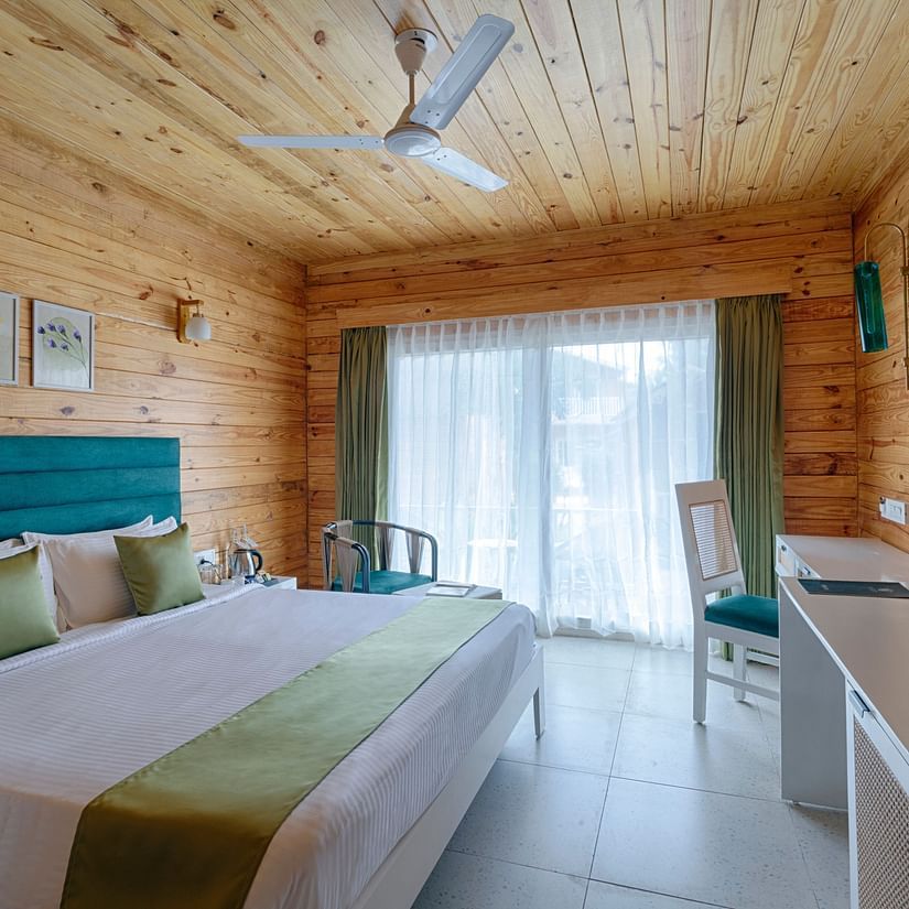 A queen bed, tv, ceiling fan and floor to ceiling sliding door to the balcony inside the cottage - - Aralea Beach Resort by Stone Wood, Morjim