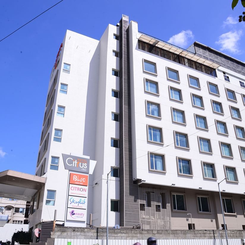 A modern multi-storey hotel building with large windows and signage, set against a bright blue sky. - Citrus Classic, Outer Ring Road, Bangalore