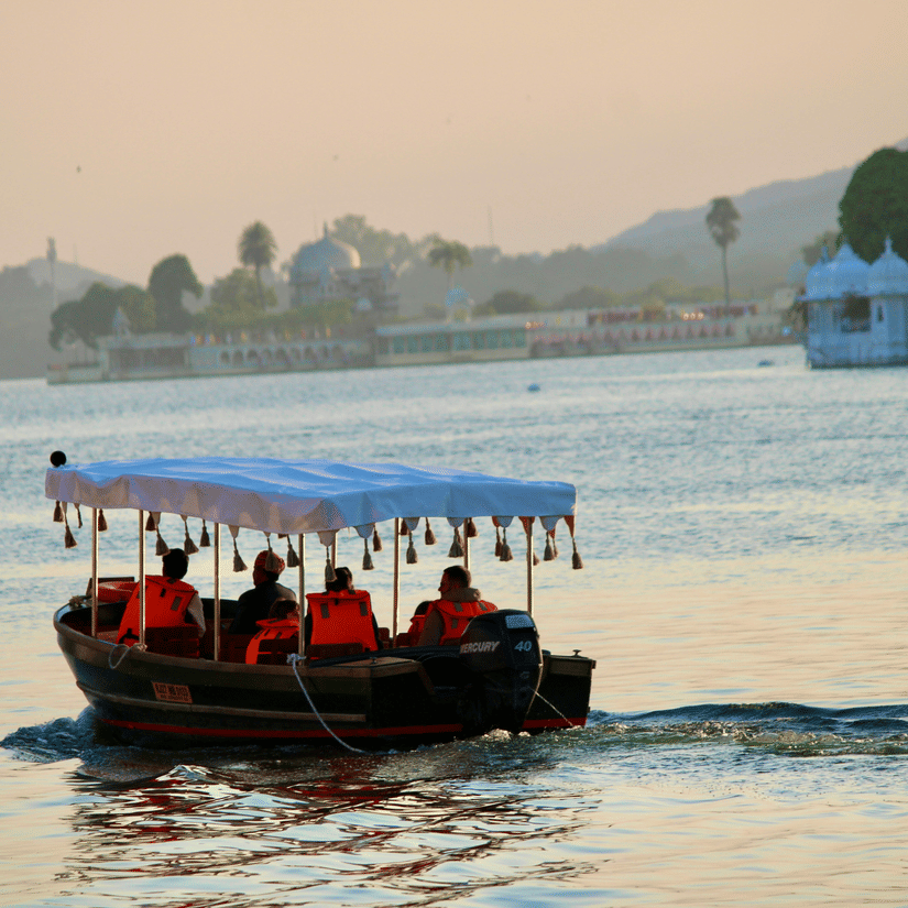 Tourist boat moving across Lake Pichola during sunset seen from the Gangaur Ghat