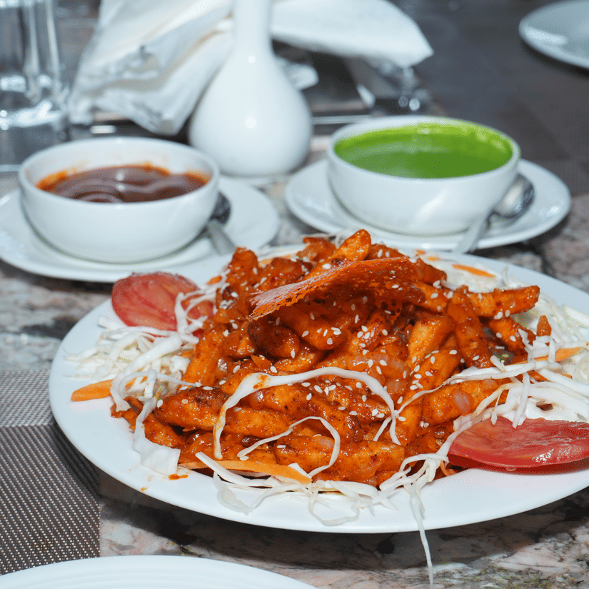 Close-up shot of a restaurant meal featuring a platter of garnished starter food, soup bowls, and water glasses on a dining table - Five Elements Hotels, Corbett Crown Resort, Jim Corbett