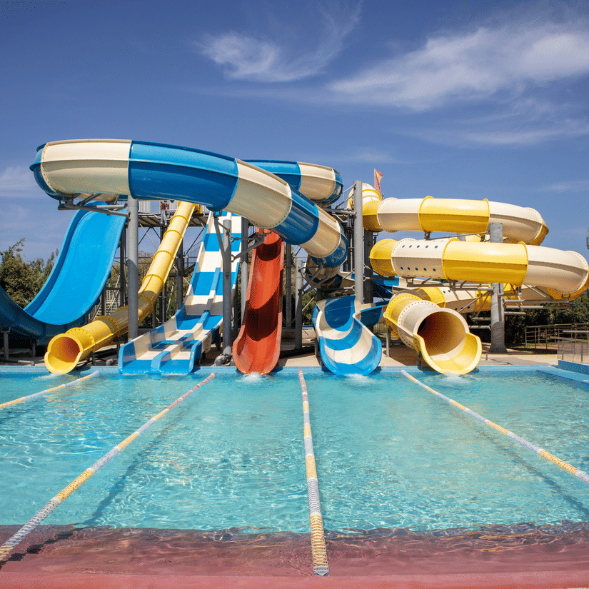 Colourful water slides emptying into a pool under a bright sunny sky.