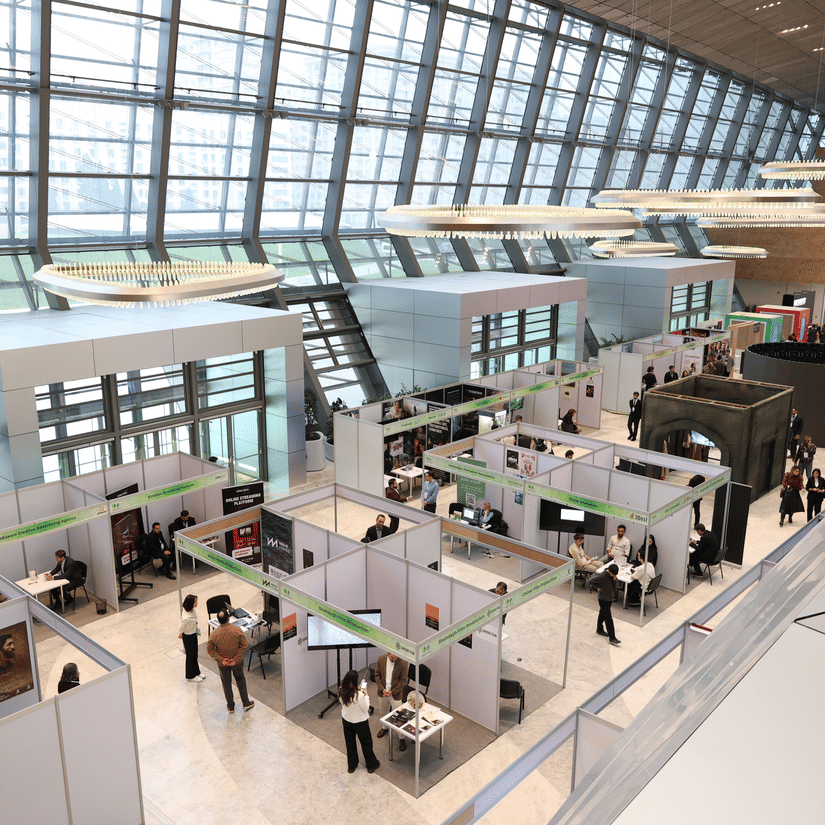 An aerial view of a convention centre with a few exhibition stands and people walking in and out of them.