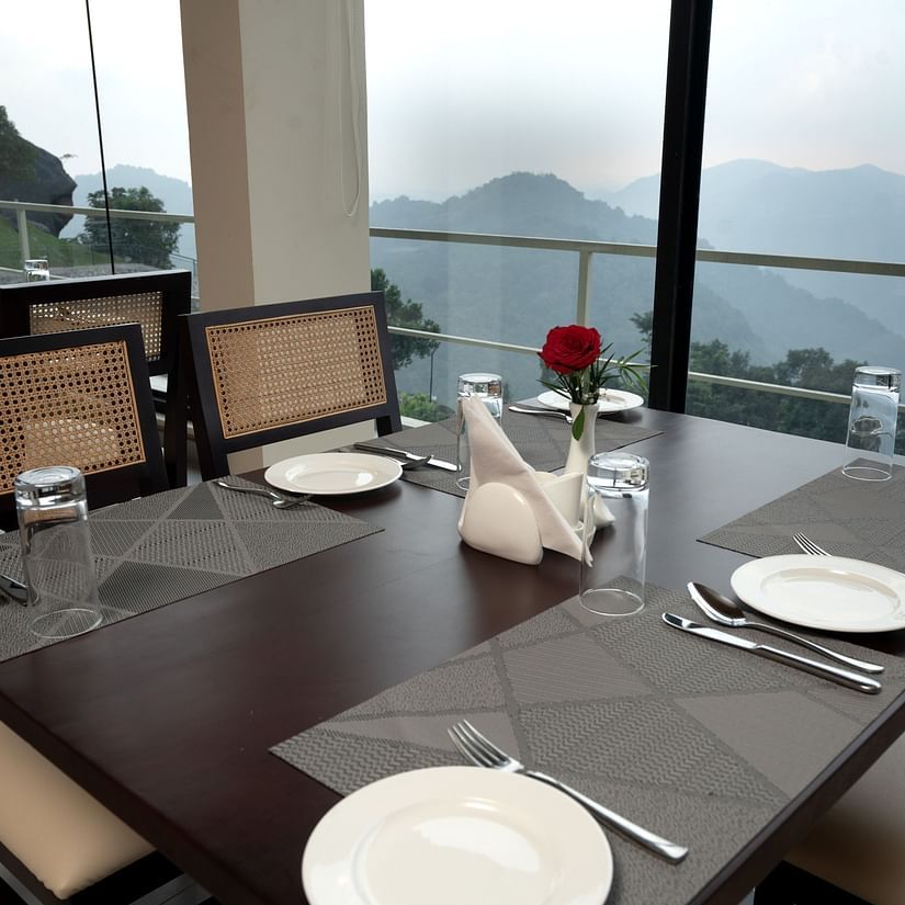 Chairs and tables with cutlery on them, beside a glass window