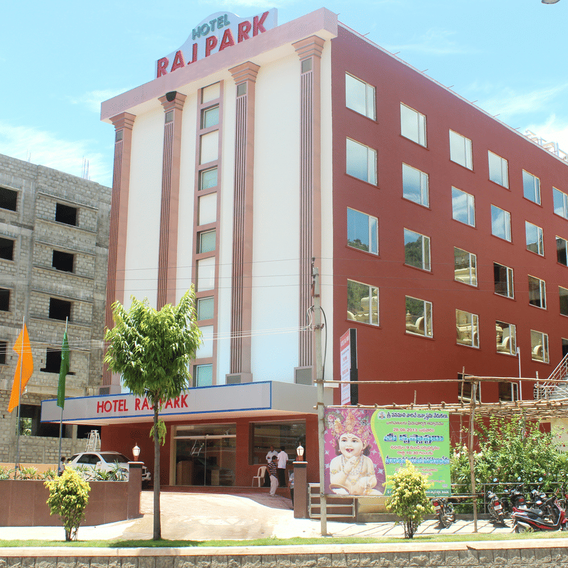 Facade of Raj Park Tirupati, showcasing a modern red-and-white exterior with a welcoming entrance in the heart of the city.