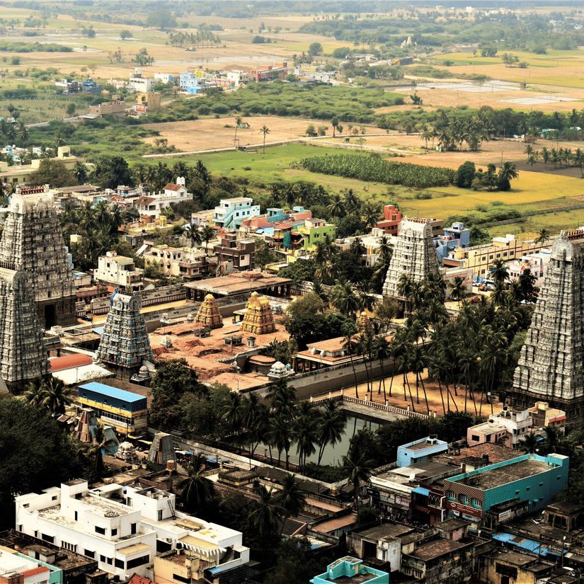 An aerial view of the town of tirupati with numerous temple's gopuram in view and other buildings and trees also in view.