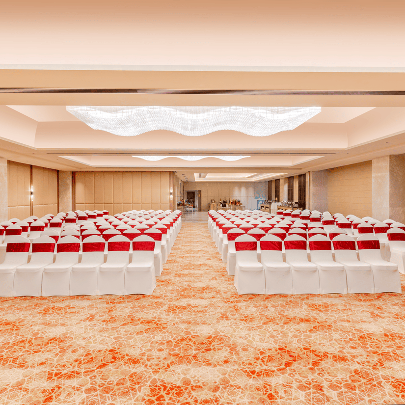 A banquet hall at Sarovar Premiere Alwar with rows of chairs and a patterned carpet on the floor.
