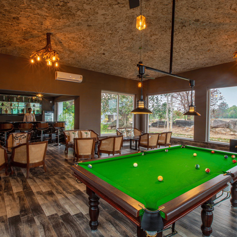 Snooker table and a bar which features several sets of table and chairs at The Riverwood Forest Retreat, Kanha.