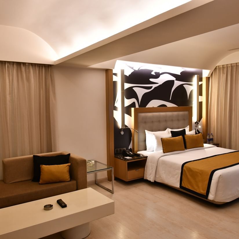 Elegant room with a king bed, table and chair with bright lighting at The Sonnet, Jamshedpur.