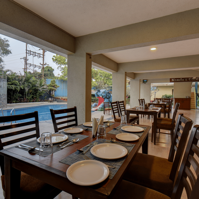 Indoor dining area with neatly arranged tables and poolside view at VITS Lonavala.