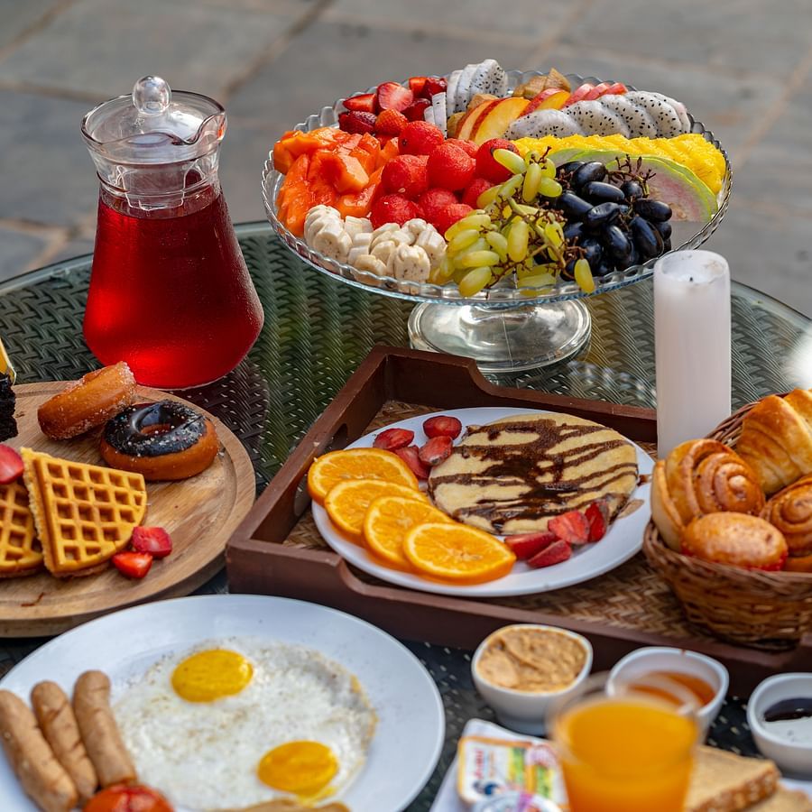An image of a dining table showcasing beverages, fruits, snacks, and baked goods.