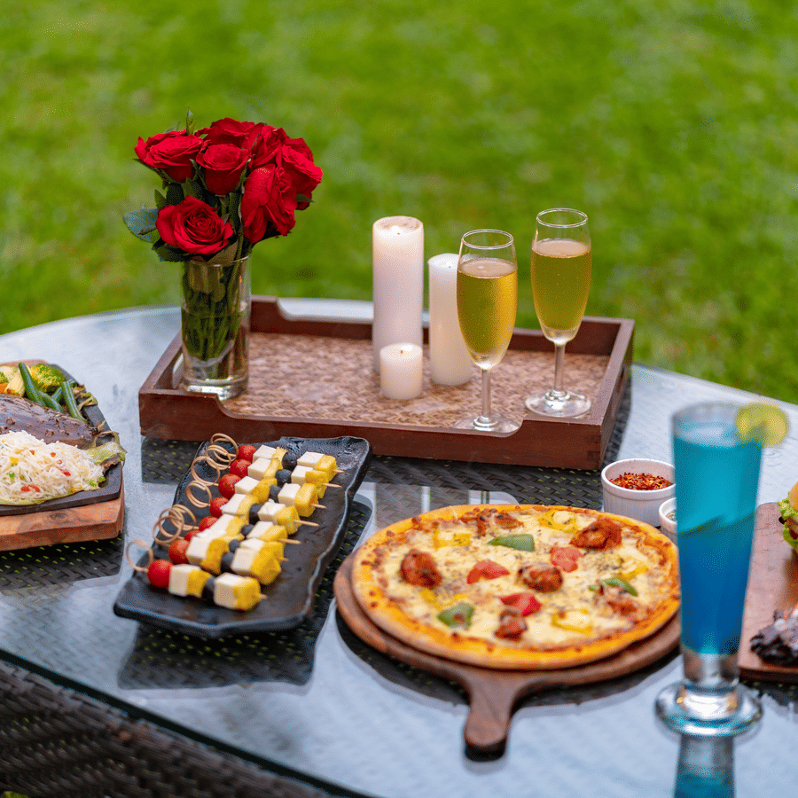 A spread of food with various food and drinks on a glass table.