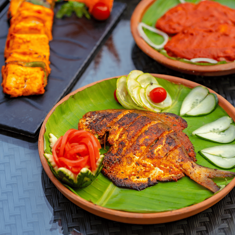 Grilled fish with salad served on a plate covered with banana leaf.