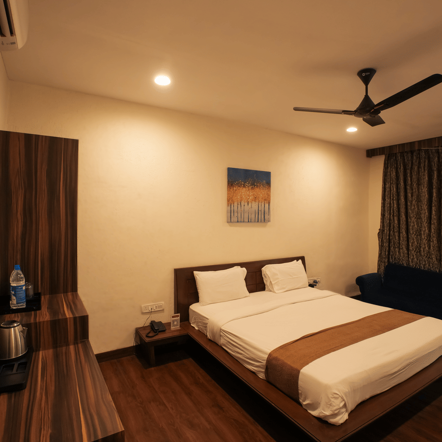 A comfortable hotel room showing a neatly made double bed, dark wood console table, and abstract wall art.