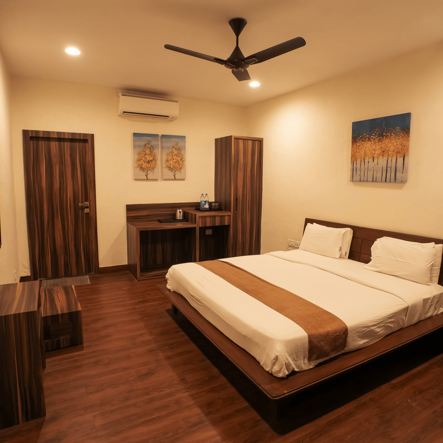 A modern resort bedroom with rich wooden flooring, a double bed, a wall-mounted TV, and minimalist decor.