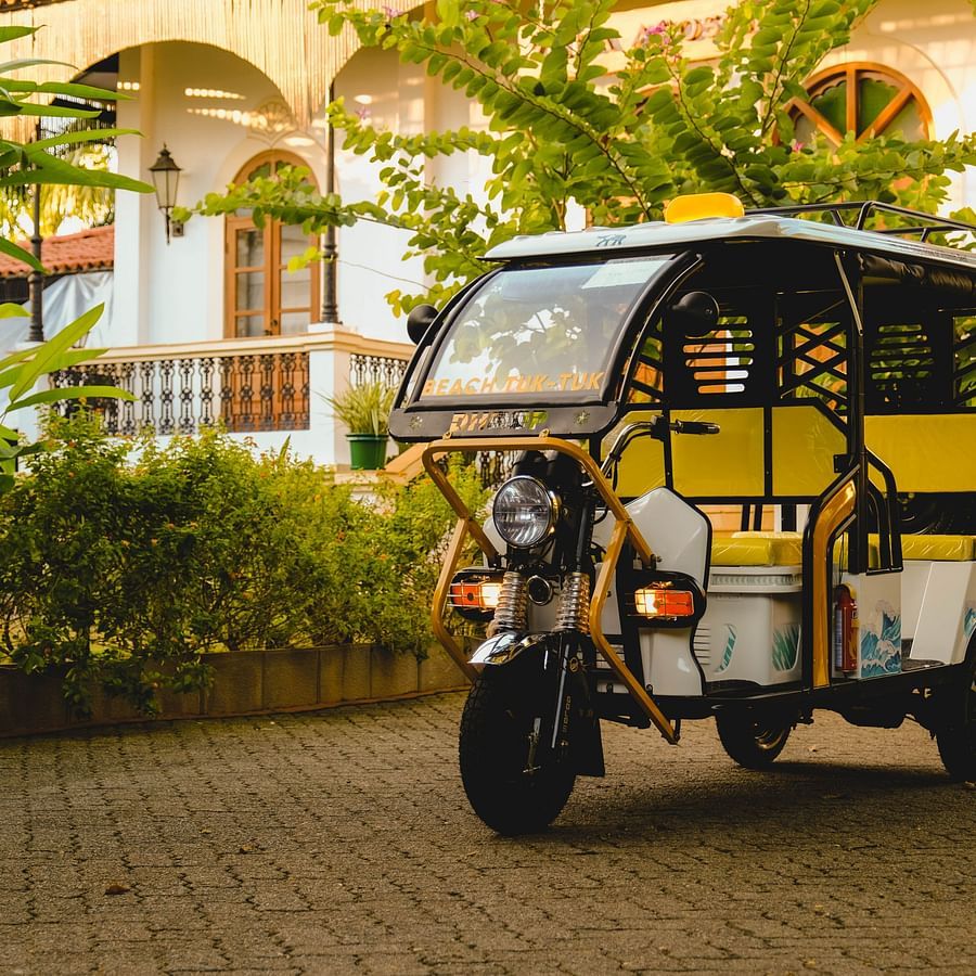 A yellow-coloured tuk tuk rickshaw with trees in the backdrop near our Goa resort with activities - Heritage Village, Goa