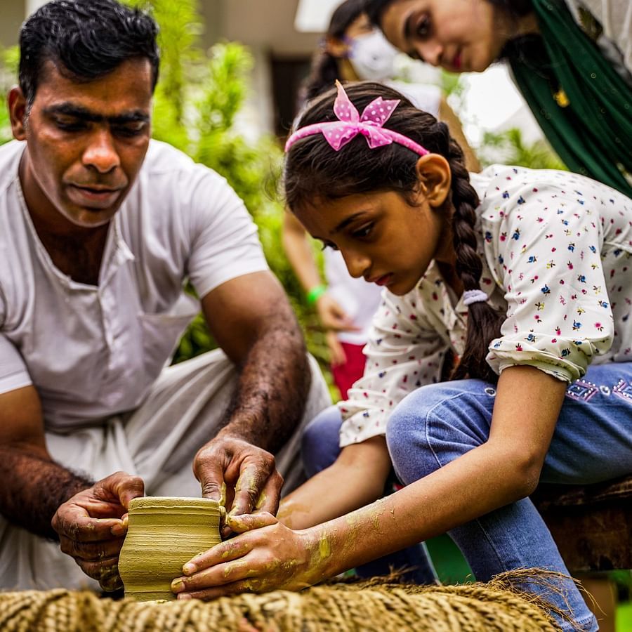 A pottery instructor teaching the art to a girl who is in working on a pot - Heritage Village, Goa