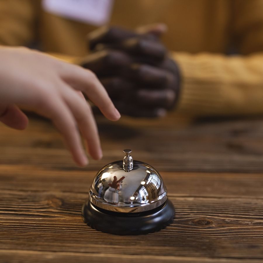 a person about to ring a reception desk bell