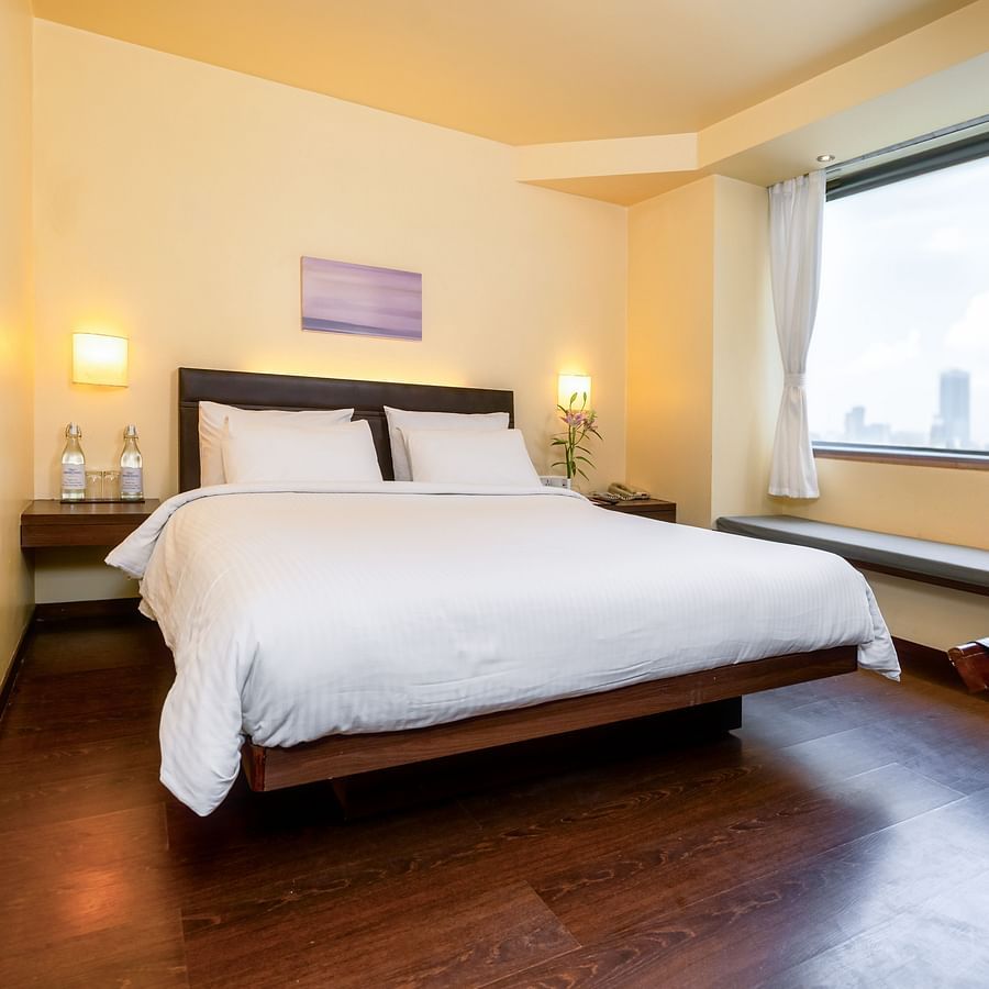 A front view off the suite  with plushy bed and a window with a wall painting  at Marasa Sarovar Portico, Rajkot
