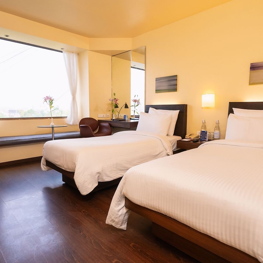 A side view of the executive bed with  comfy twin beds and a window with a view at Marasa Sarovar Portico, Rajkot