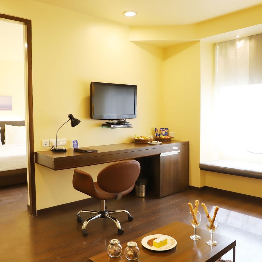 An image of the seating area in Suite with working desk and tv at Marasa sarovar Portico,Rajkot