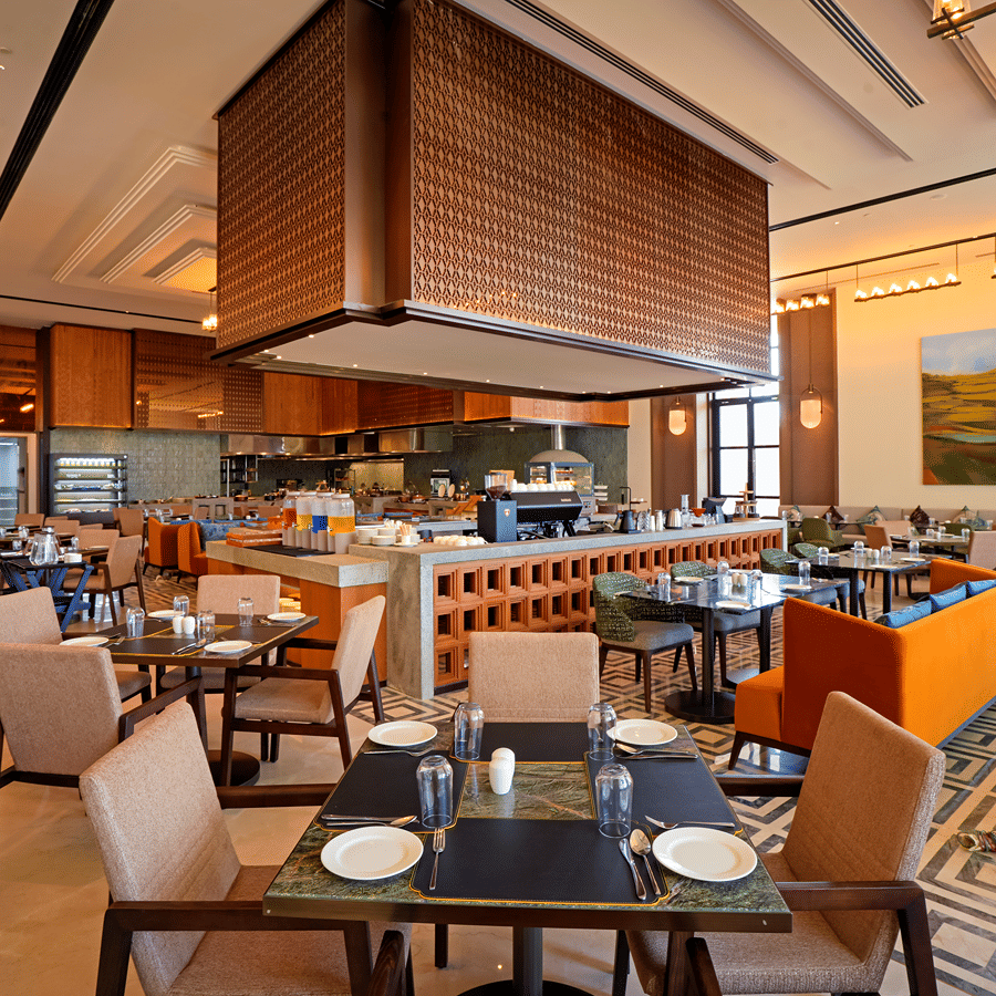 Dining area with an open kitchen counter and warm wood accents at Chithirai restaurant, The Residency Signature Madurai, offering a relaxed setting