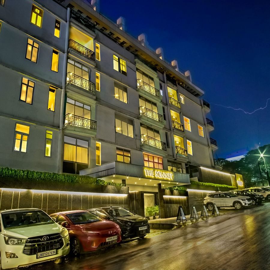 A multi-story apartment building at night with illuminated windows and parked cars in front- The Sonnet, Kolkata