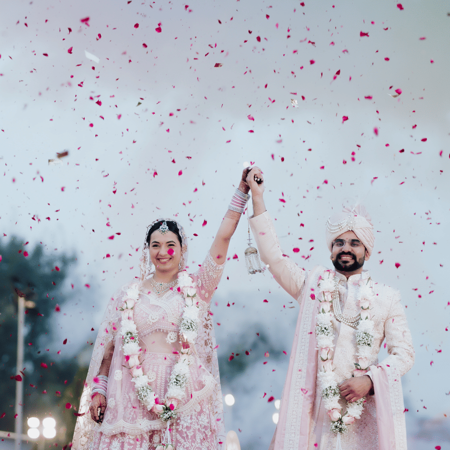Bride and groom celebrating with confetti during a wedding ceremony at Umaid Palace.