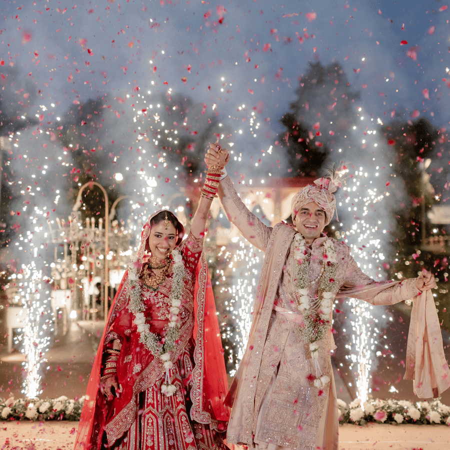 Bride and groom making a grand wedding entry with fireworks at Umaid Palace.