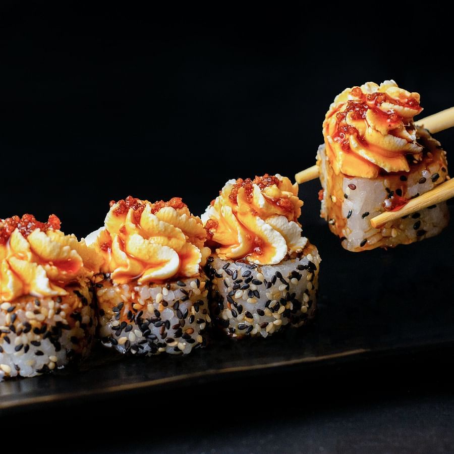 an image of a japanese dish called sushi being picked up by chopsticks from a plate