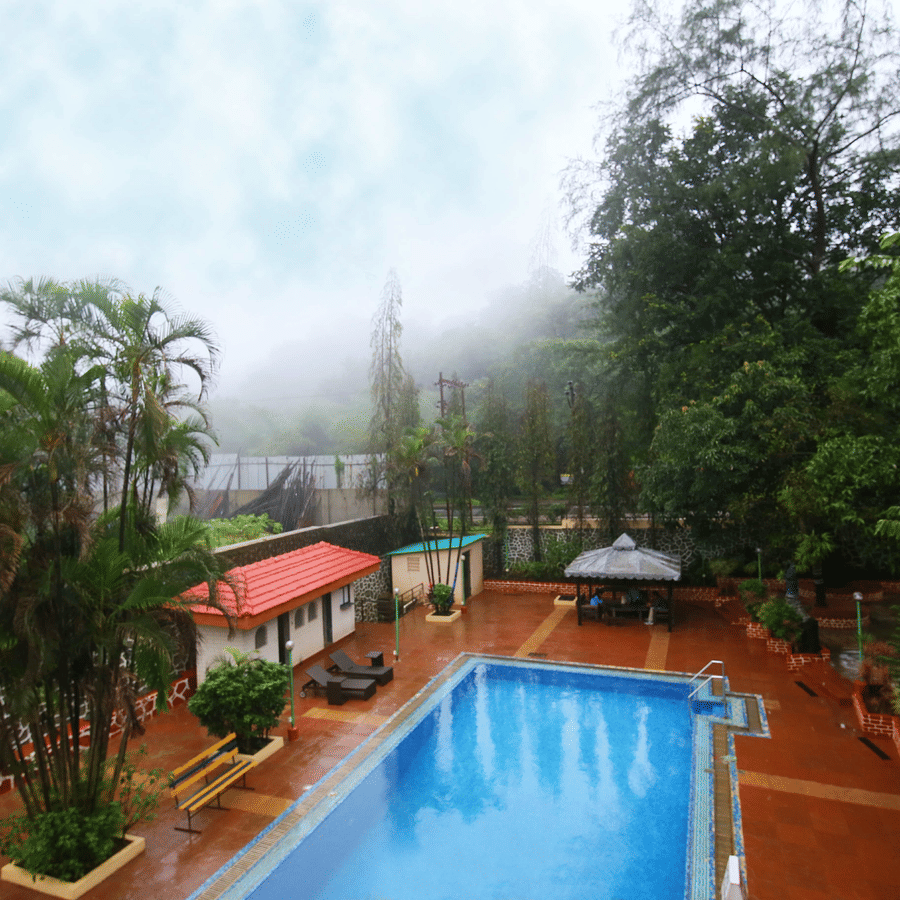A tranquil swimming pool sits at the heart of a lush garden with mist lingering among the trees | Zara's Resort