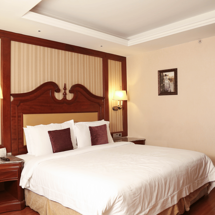Spacious king bedroom with wooden flooring, warm lighting, and elegant interiors for comfortable day stays near Chennai airport | Hablis Hotel Chennai