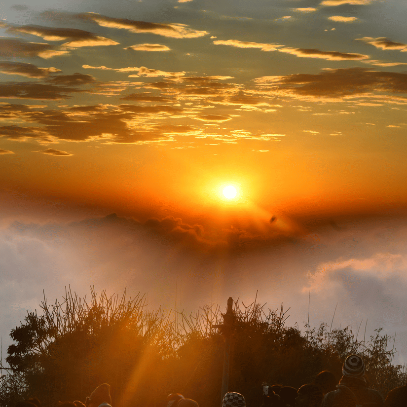 Golden sunrise above clouds at Tiger Hill with warm light spreading across the Himalayan horizon.