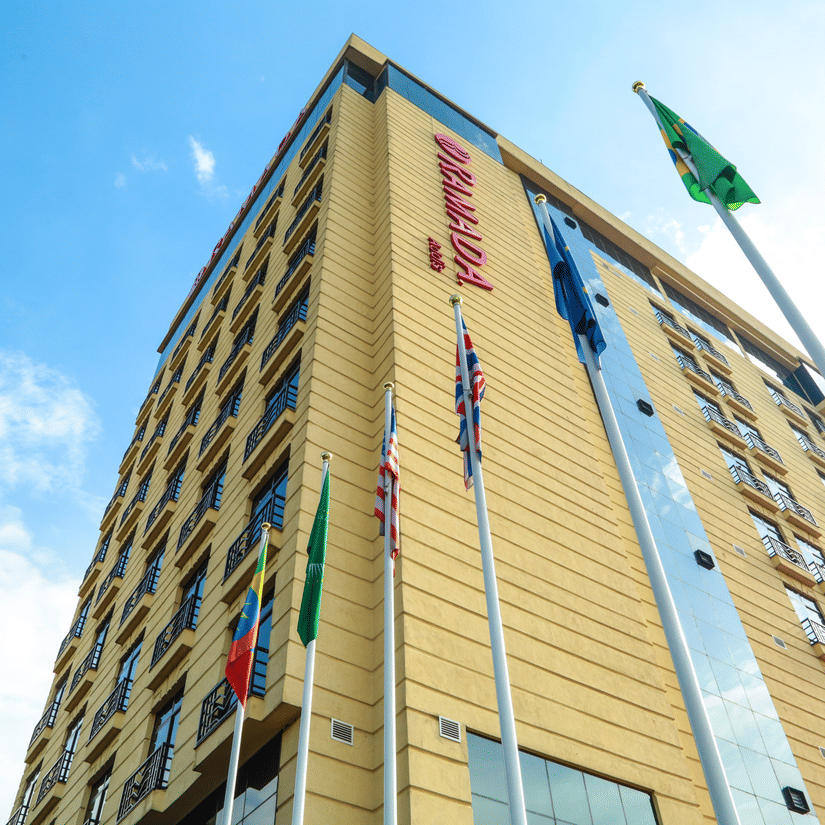 Facade of Ramada by Wyndham Addis, Addis Ababa, with blue sky in the background and flags lined up in front of the building