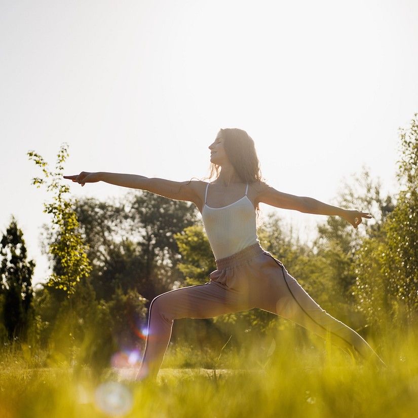 a woman doing a yoga pose during daytime while the sun shines
