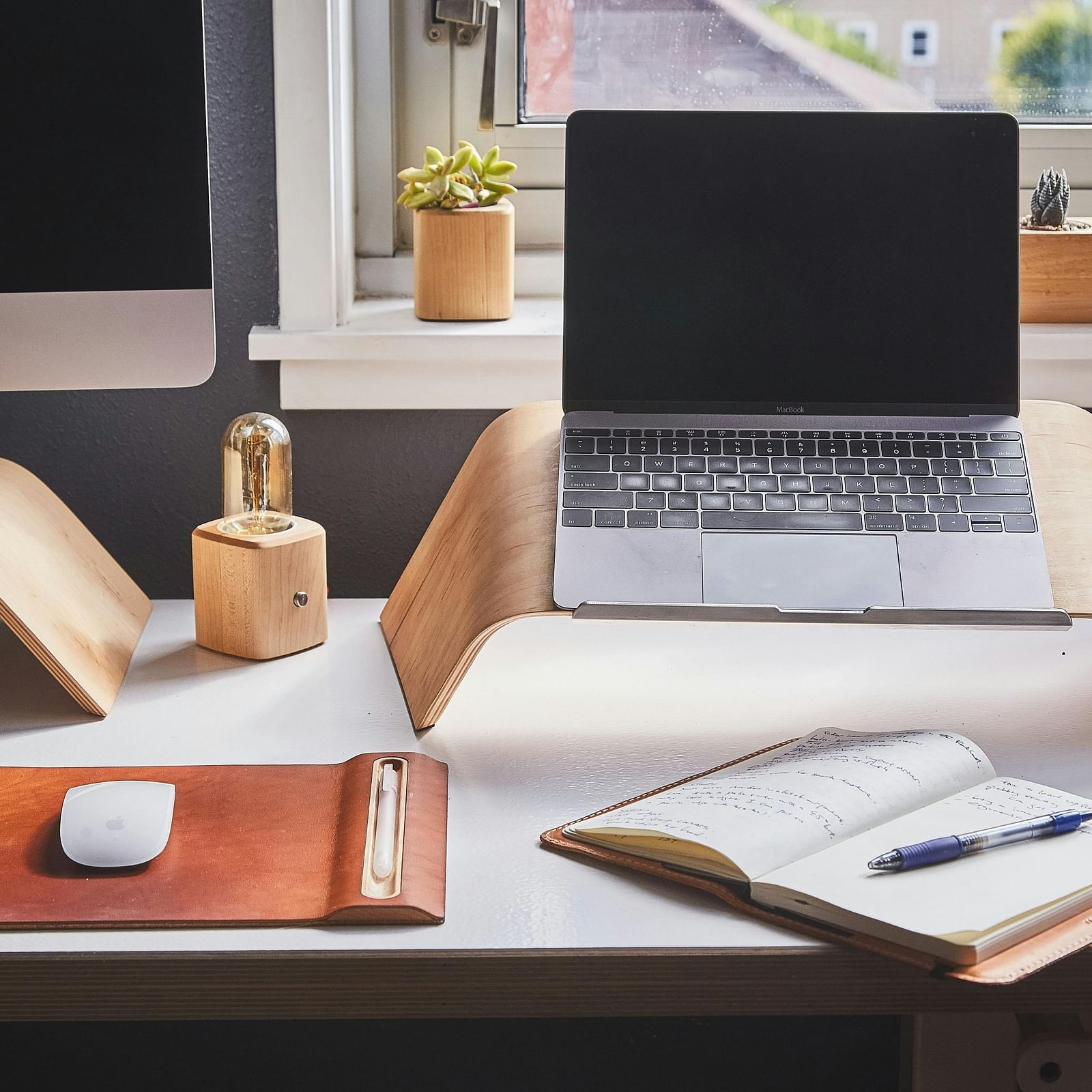 An image of a work desk which has a latptop, notebook, and other items