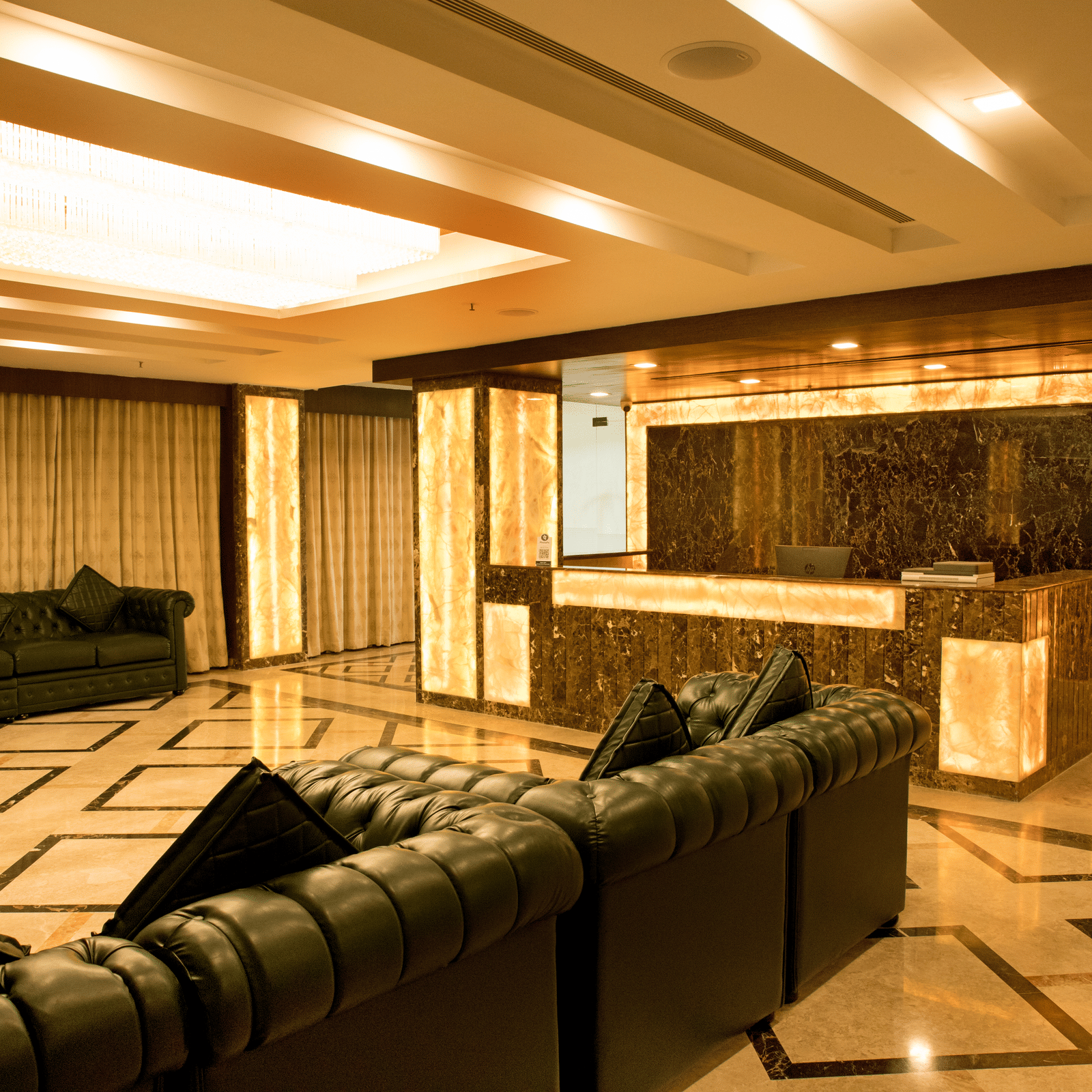 A well-lit hotel lounge at Benzz Park Chennai featuring several comfortable sofas arranged for social gatherings.