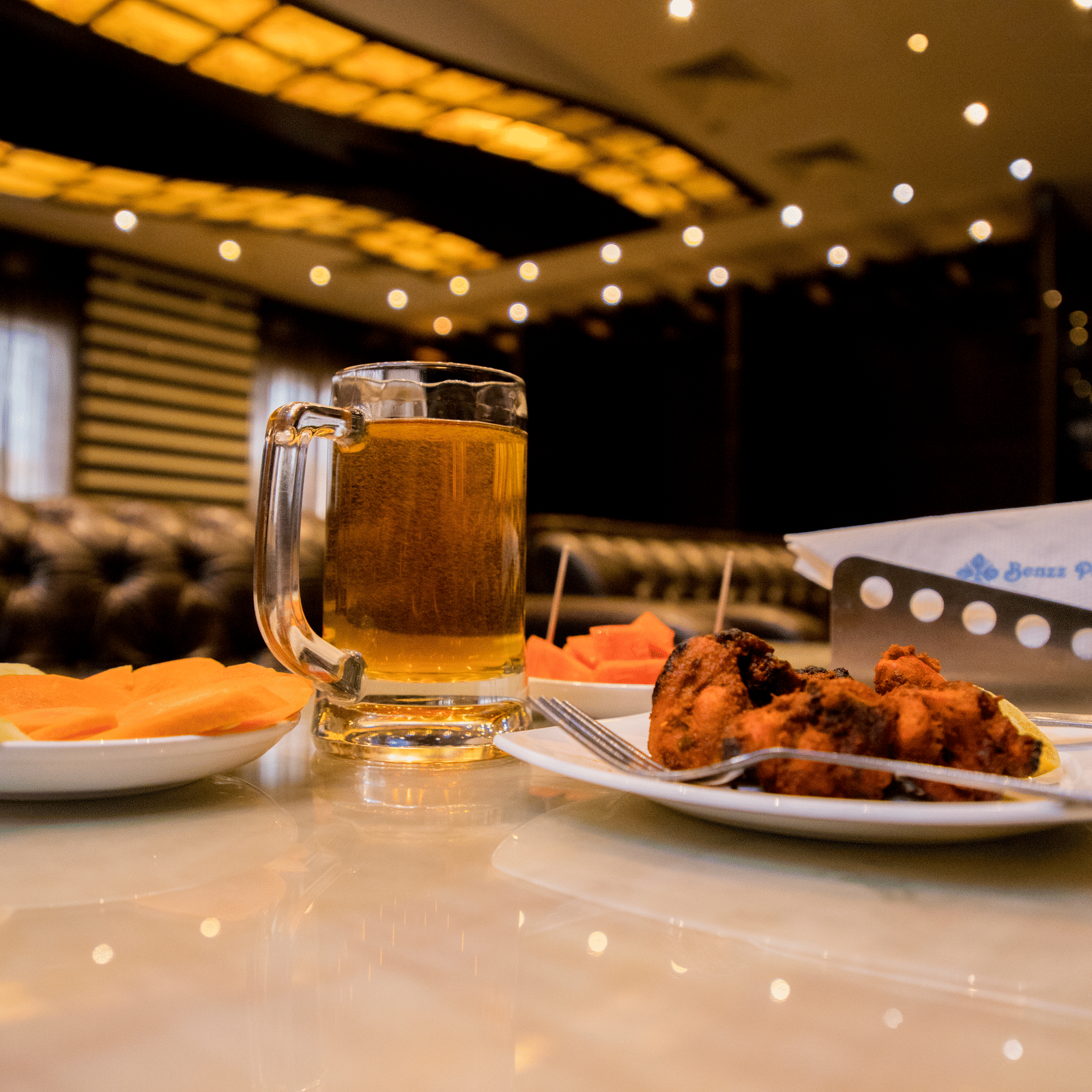 A close up shot of delicious side dish served with a plate of salad and a pint of beer on a dining table at Benzz Park, Vellore.