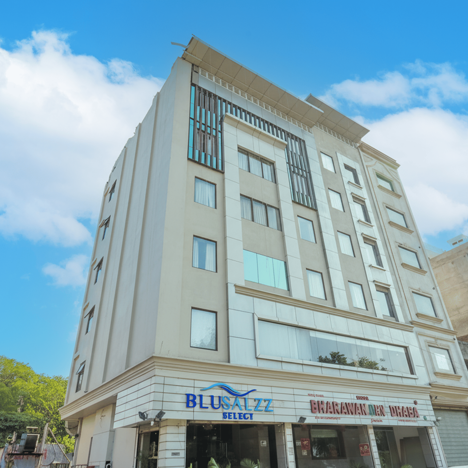 A slightly distant view of a modern hotel building under a blue, cloudy sky, highlighting the clean, vertical facade and large windows at BluSalzz Select City Centre, Amritsar.