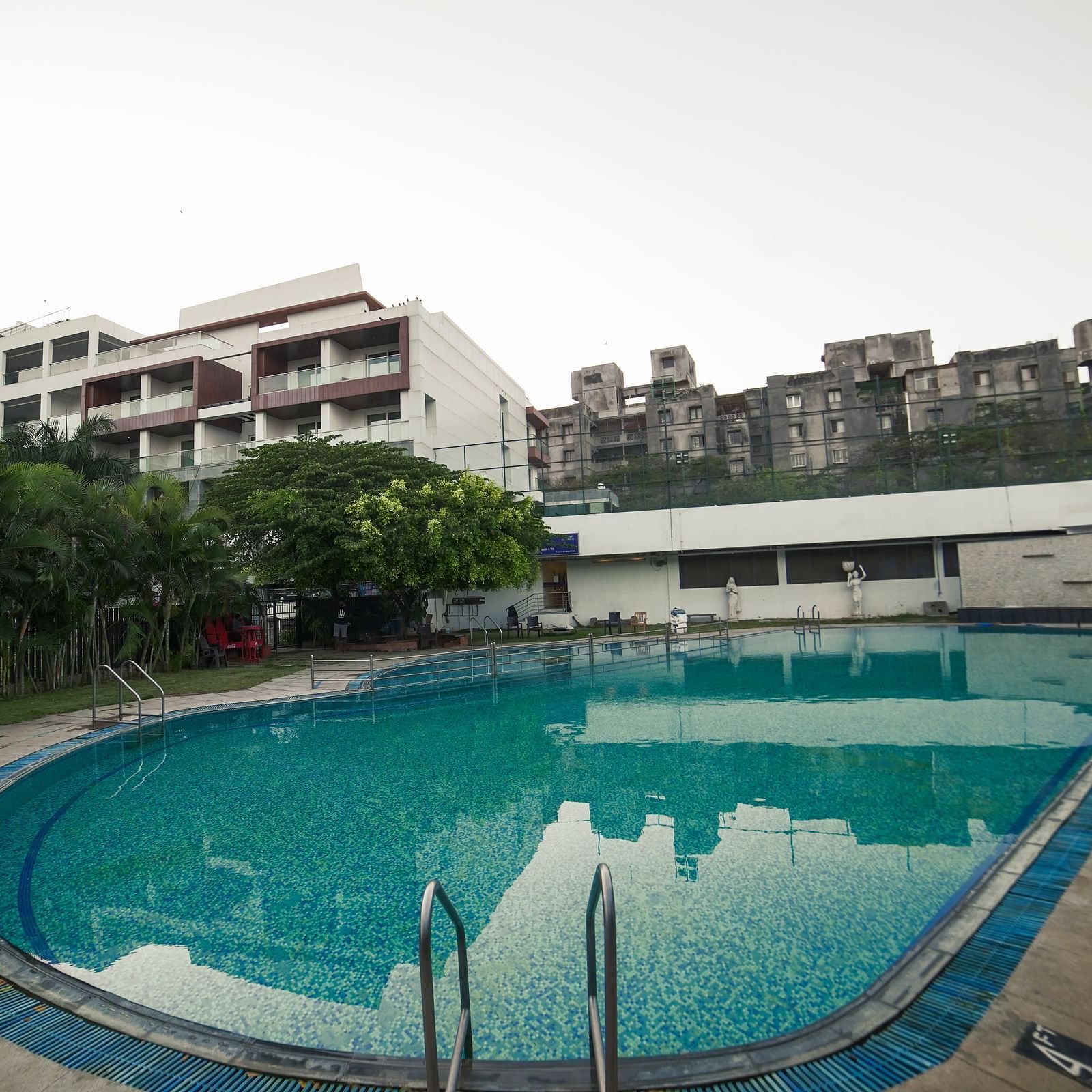 An outdoor swimming pool with blue water and surrounding buildings, part of BNGV Grandeur Hotel and Banquets.
