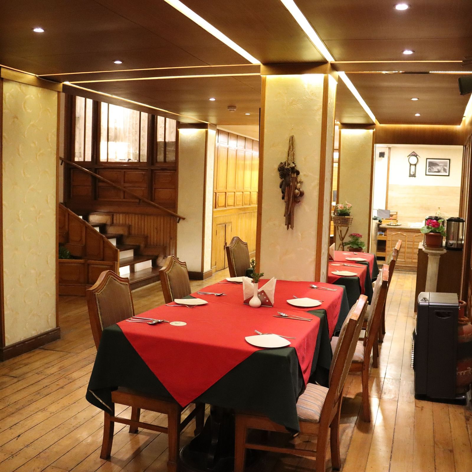 Dining area at Cedar Inn, Darjeeling, featuring spacious seating arrangements, neatly placed cutlery, overhead lighting and a CCTV.