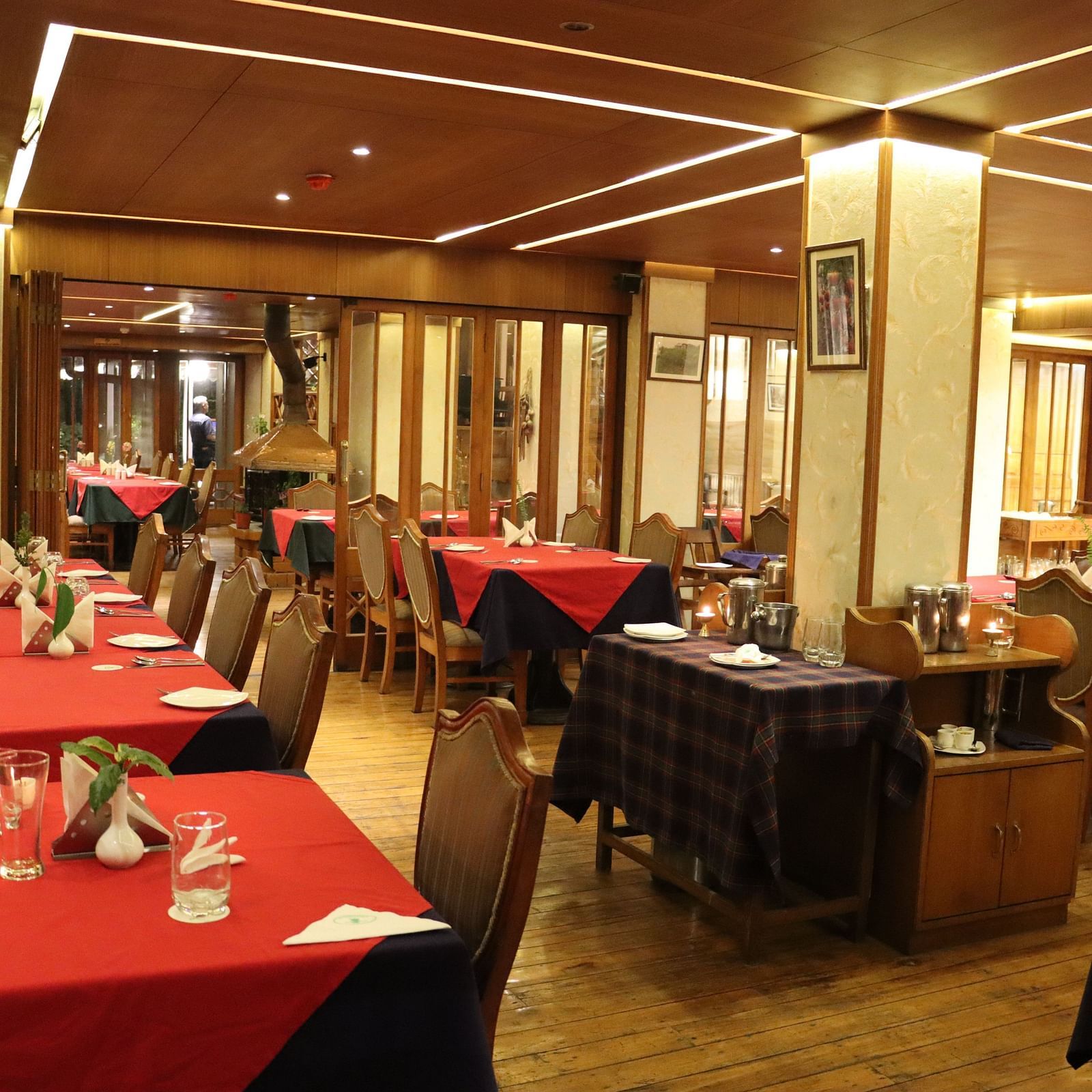Parallel and spaciously arranged dining tables with respective cutlery placements in the dining space at Cedar Inn, Darjeeling