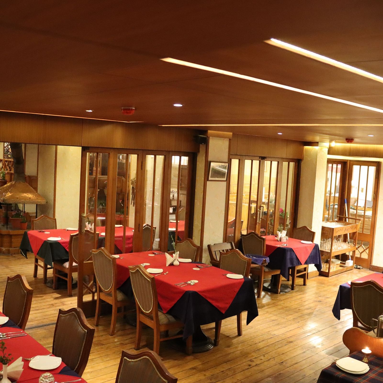 Parallel and spaciously arranged dining tables with respective cutlery placements in the dining space at Cedar Inn, Darjeeling