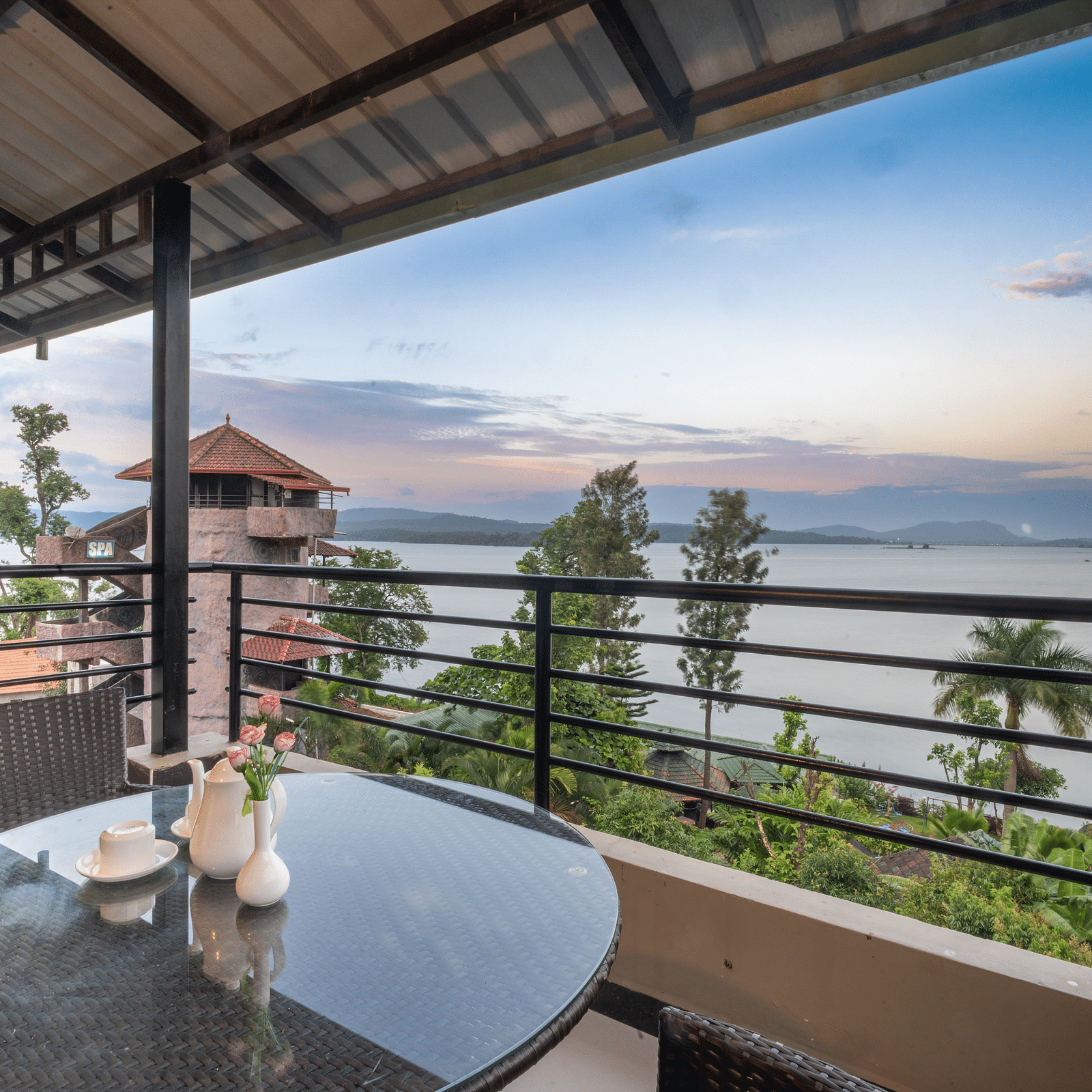 Image of a balcony with seating area overlooking a water body and plants surrounding it at Coorg Jungle Camp Backwater Resort, Kushalnagar.