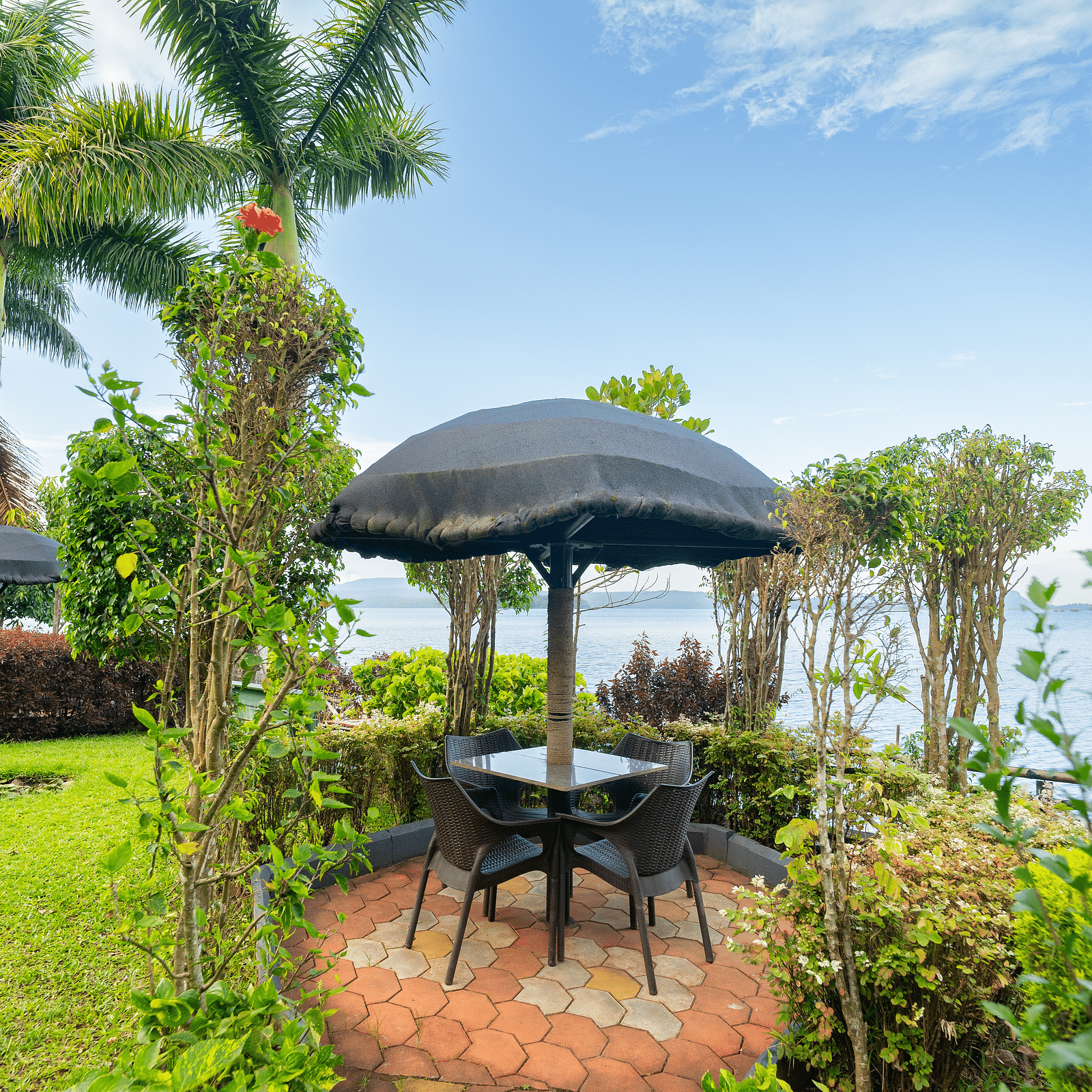A seating area with tress around it and a waterbody in the background at Coorg Jungle Camp Backwater Resort, Kushalnagar.