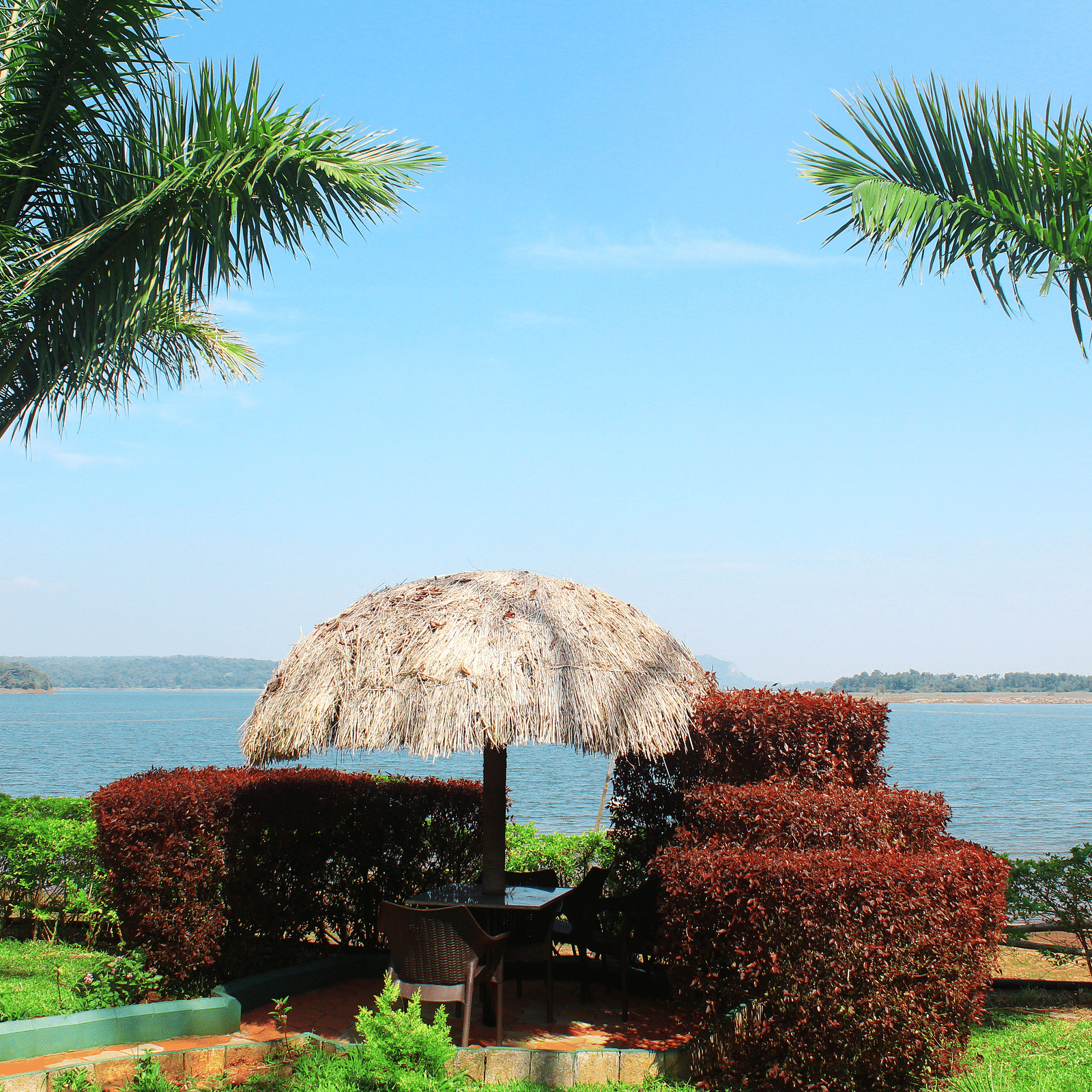 View of a gazebo with two trees and a water body in the background at  Coorg Jungle Camp Backwater Resort, Kushalnagar.