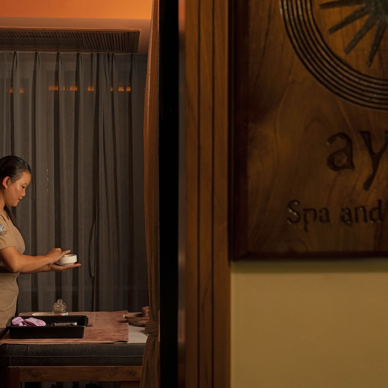 Ayur Spa at Coral Reef Hotel and Spa in Port Blair featuring a masseuse preparing essentials for spa holding a little bowl