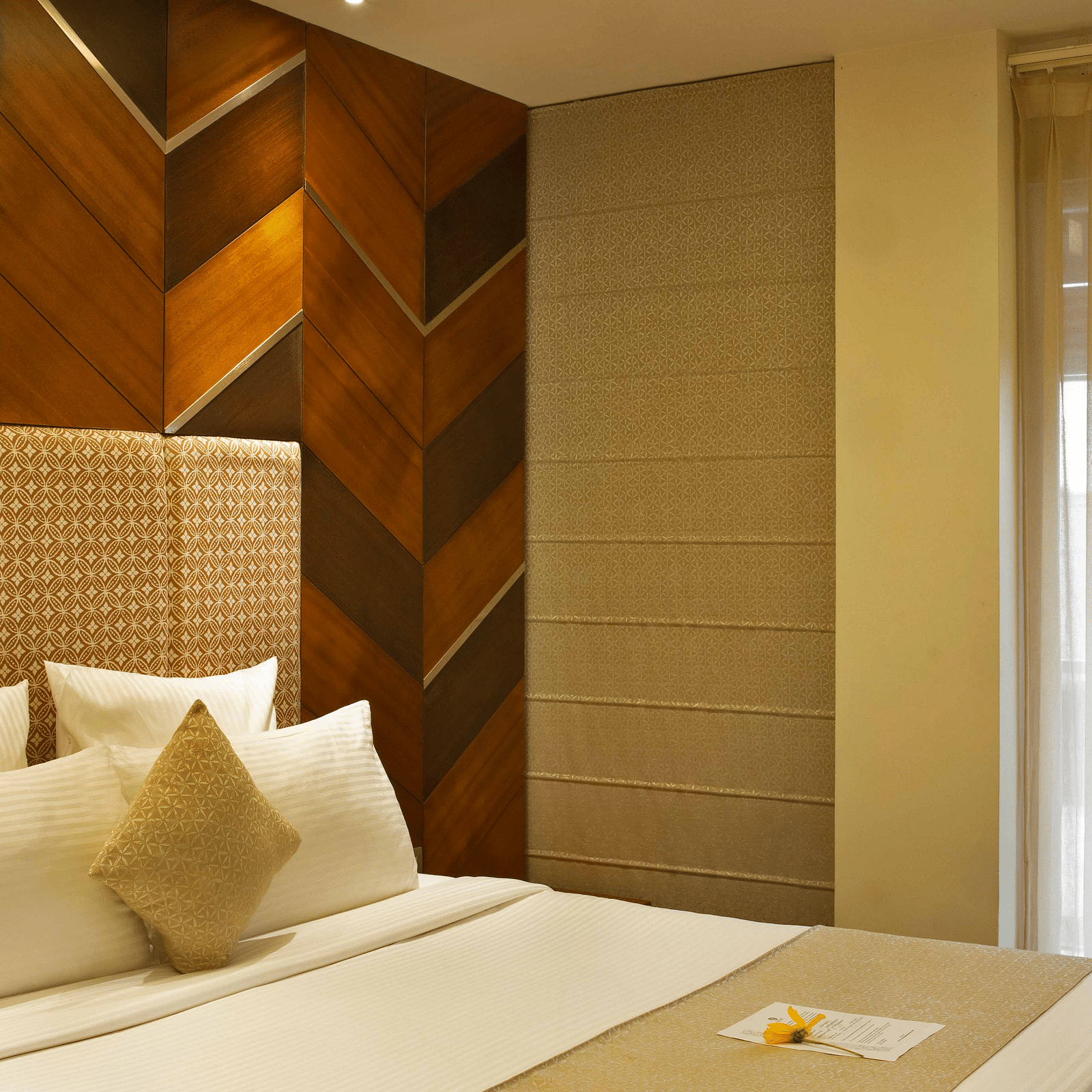 Image of Coral Suite at Coral Reef Hotel and Spa in Port Blair featuring a plush bed with pillows and cushions on it next to the door to balcony
