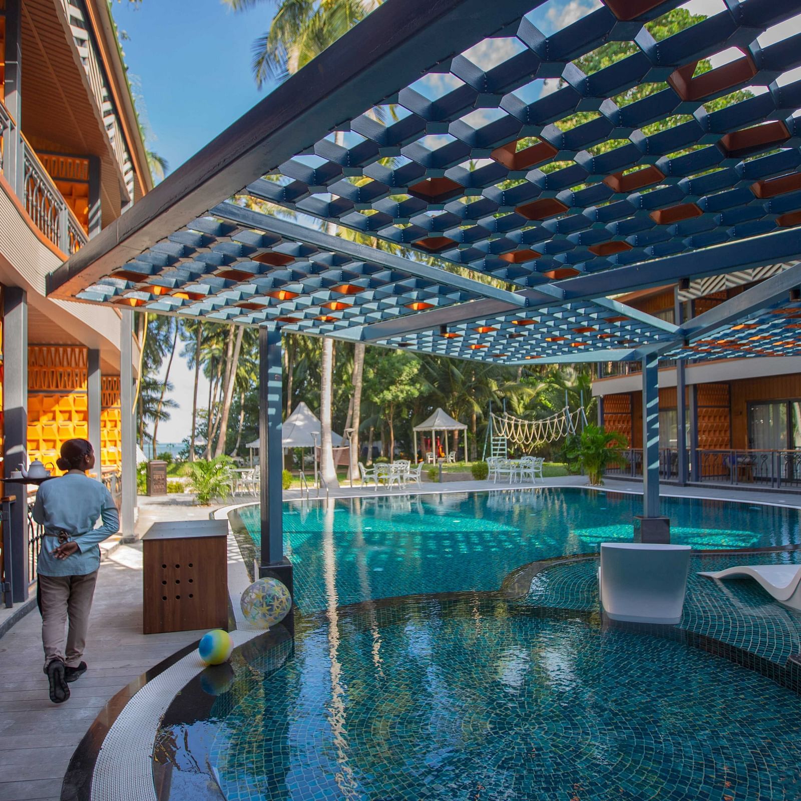 A stylish outdoor pool area featuring a modern wooden pergola and tropical plants. The pool is surrounded by comfortable seating and offers a relaxing environment - Coral Reef Resort & Spa, Havelock