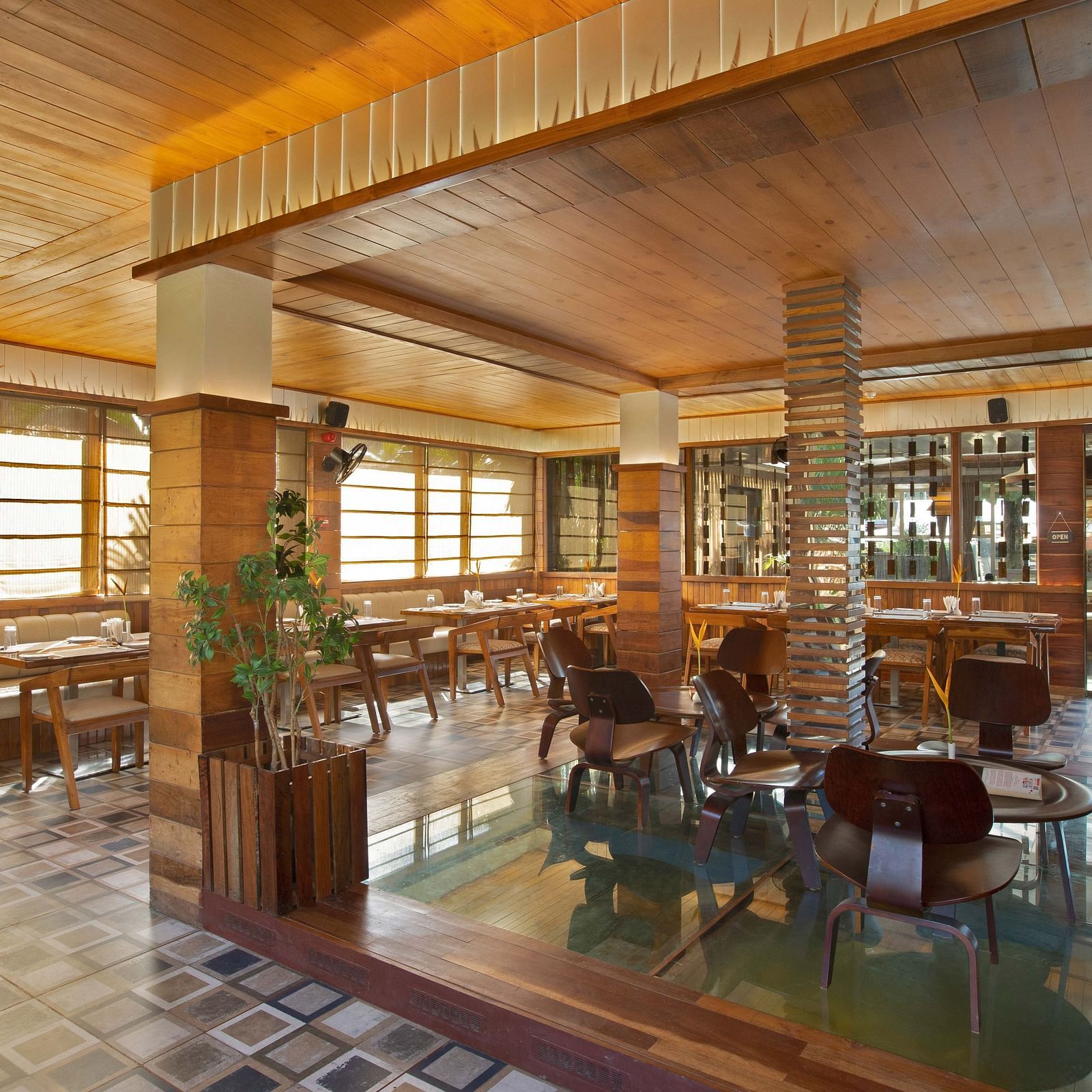 An elegant restaurant interior of Ocean Prime with wooden beams and tasteful decor. The space features a combination of dining tables and tropical plants, creating a warm, inviting vibe - Coral Reef Resort & Spa, Havelock