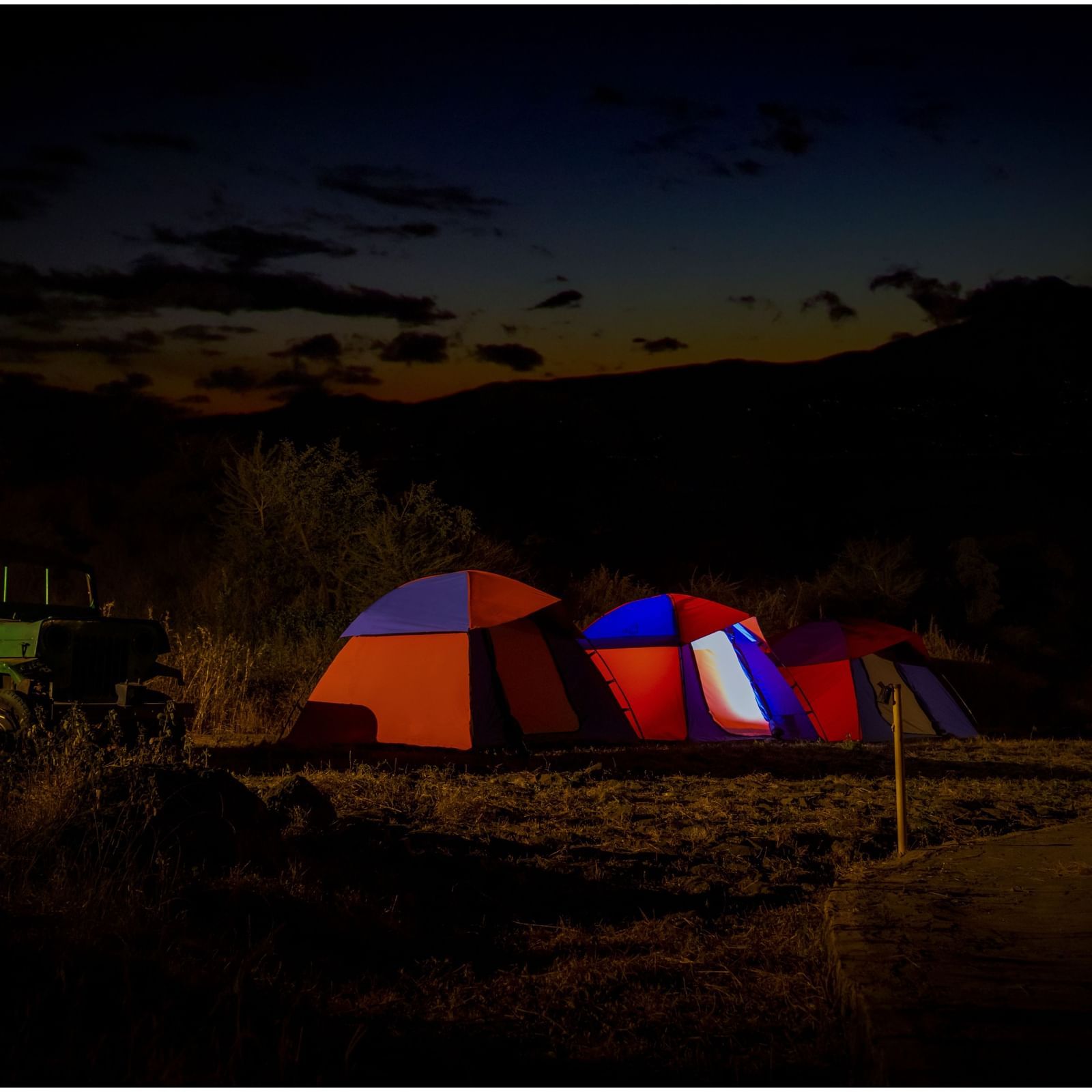 Illuminated camping tent set up on a mountain landscape under night sky | Diamond Parks, Pune